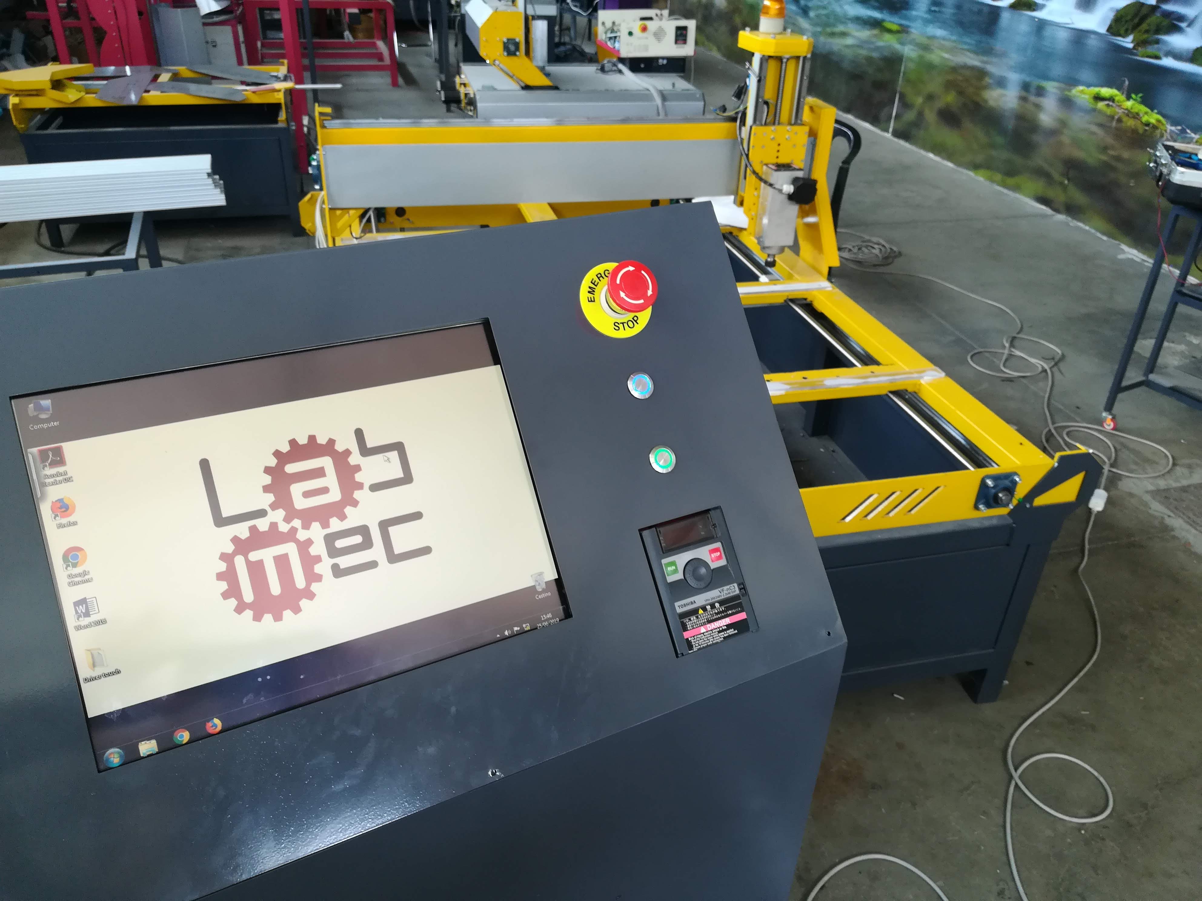 Postazione di controllo LabMec con monitor e pulsantiere, collegata a macchina CNC per lavorazioni automatizzate