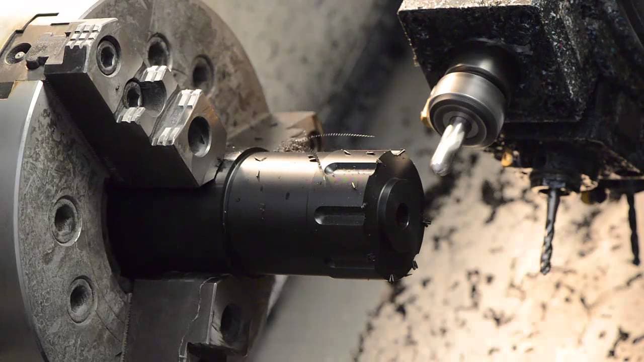Dettaglio ravvicinato di una lavorazione meccanica su metallo con macchina CNC, con utensile in azione e trucioli in fase di asportazione.